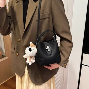 Minimalist black pebble leather bucket bag with silver clasp and cute puppy charm accessory