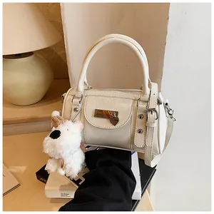 Detail der cremeweißen Bowling-Tasche mit strukturiertem Leder, Herzanhänger und Welpen-Charme