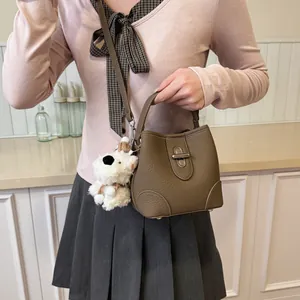 Brown lychee leather bucket bag with top handle and plush puppy pendant accessory
