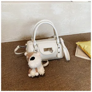 Detailansicht einer weißen Boston-Tasche mit Herzanhängern und weißem Plüschhund-Zubehör