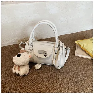 Detail der cremefarbenen Boston-Tasche mit Herzanhänger und Plüschhund-Accessoire