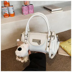 Detail einer weißen zylindrischen Boston Bag mit Herz-Metallschließe und Plüsch-Hundeanhänger