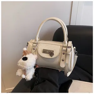 Nahaufnahme cremefarbene Bowlingtasche mit Silberbeschlägen und Plüschhund-Anhänger