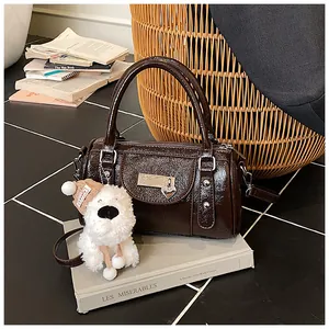 Detail der dunkelbraunen Boston Bag mit Herzschloss und weißem Plüsch-Hundeanhänger