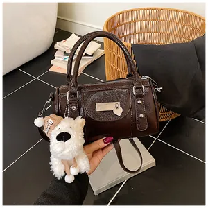Nahaufnahme der schokobraunen Leder-Bowling-Tasche mit Herzanhänger und Plüschwelpe