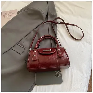 Detail der dunkelroten glänzenden Leder-Pillow-Bag mit Metallschnallen und Nieten