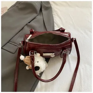 Detail der burgunderroten Boston-Tasche mit Plüschbären-Anhänger auf Anzughintergrund