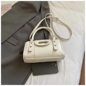 Detailaufnahme der cremefarbenen Ledertasche mit Silberbeschlägen auf dem Bett
