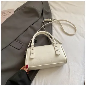 Detailaufnahme einer cremefarbenen Bowlingtasche mit Nieten auf einem grauen Anzug