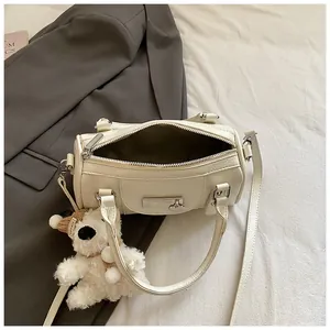 Detail der cremeweißen Leder-Bowlingtasche mit süßem Plüschwelpen-Anhänger und Silberbeschlägen