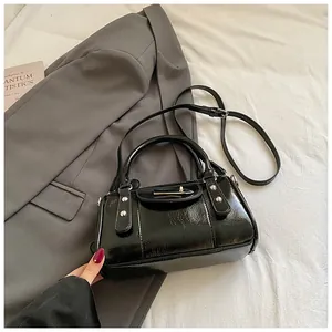 Details einer glänzenden schwarzen Boston-Bag mit Nieten und verstellbarem Trageriemen