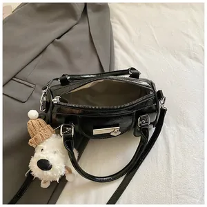 Draufsicht auf schwarze Lackleder-Bowlingtasche mit weißem Plüschhund-Anhänger und Futter
