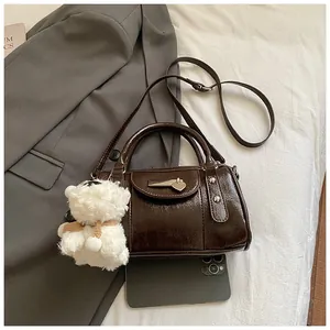 Detail der dunkelbraunen Vintage-Kegeltasche mit Herzdekor und Plüschbär-Anhänger