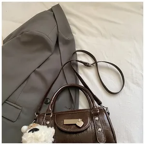 Detail der dunkelbraunen Lack-Bowlingtasche mit Herzanhänger und Plüschschaf-Accessoire