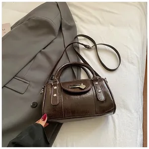 Detailansicht der dunkelbraunen Lackledertasche mit Herz-Metallverzierung und Nieten
