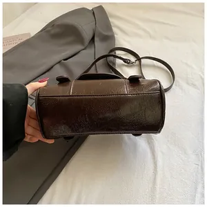 Detailaufnahme einer dunkelbraunen Glanz-Bowlingtasche mit glatter Textur und Schutzfüßen