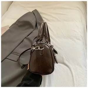 Detail der dunkelbraunen Boston-Tasche in Glanzoptik mit Knitterstruktur und Silber-Elementen