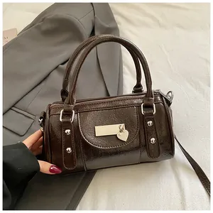 Detail der dunkelbraunen Lackleder-Bowlingtasche mit Herzanhänger und Silbernieten