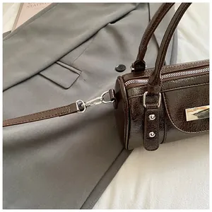 Detail der dunkelbraunen Lackleder-Bowlingtasche mit Silber-Hardware und Logo-Plakette