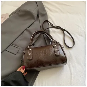 Detailansicht der dunkelbraunen Glanz-Handtasche mit Silbernieten und Schultergurt