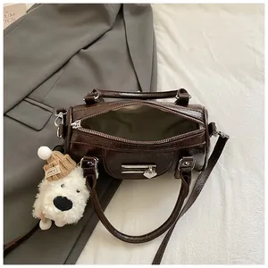 Detail der dunkelbraunen Leder-Bowlingtasche mit Glanzfinish und Plüsch-Hundeanhänger