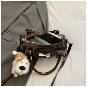 Details der dunkelbraunen glänzenden Boston Bag mit Innenraum für Handy und süßem Anhänger