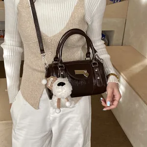 Braune Boston Tasche aus Leder mit Plüschanhänger am Modell im minimalistischen Stil
