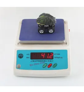 Macro shot of a green dinosaur pull-back toy car showing weight of 41.2g on a digital scale