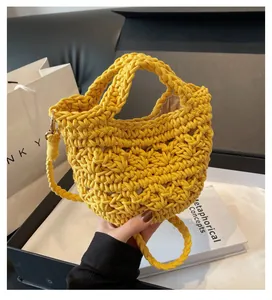 Detail of yellow hollow crochet bucket bag with metal hooks and detachable woven strap