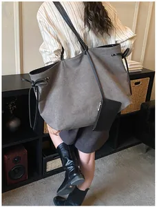 Spacious grey canvas tote bag with black leather straps and side bow details on model