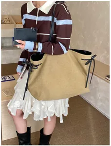 Close-up of khaki tote bag with black ribbon bows and matching small clutch pouch