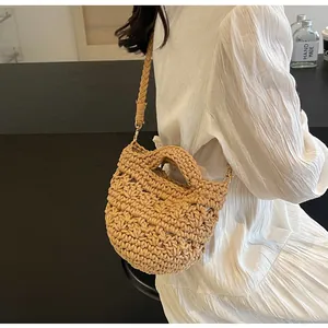 Detail of a handmade crochet crossbody bag with beige woven texture and soft bucket shape