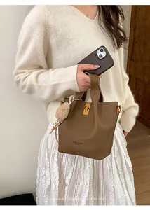 Detail of brown lychee pattern bucket bag featuring a gold twist lock and furry charm