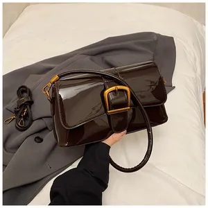 Detailansicht der dunkelbraunen Lacklederstruktur und der goldenen Schnalle der Tasche