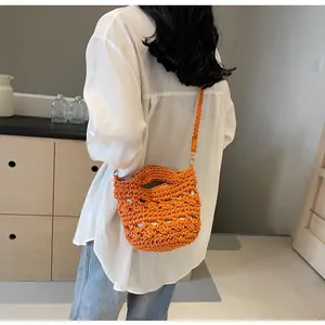 Detail of orange crochet bucket bag showing hand-woven texture and shoulder strap