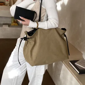 Minimalist khaki suede tote bag with black drawstring details and matching pouch
