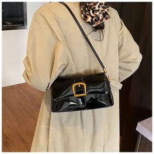 Detailansicht einer schwarzen Lackleder-Schultertasche mit goldener Schnalle und Riemen