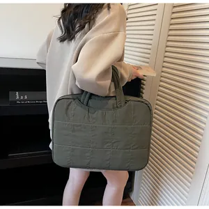 Detail of army green quilted laptop bag with square stitching held by a model