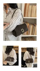 Close-up of a retro dark brown crossbody bag with a distinctive gold metal buckle