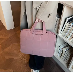 Close-up of dust pink quilted laptop bag featuring classic square stitching and top handles