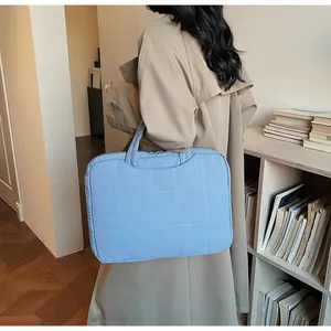 Gros plan d'un sac à main matelassé bleu clair porté par un mannequin dans un bureau
