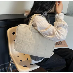 Detail of cream quilted tote bag showing square stitching and soft nylon texture