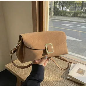 Detail of a dark brown suede crossbody bag with elegant square gold metal buckle