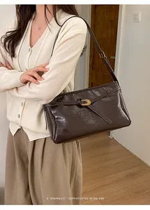 Close-up of retro dark brown glossy leather tote featuring a gold oval buckle detail