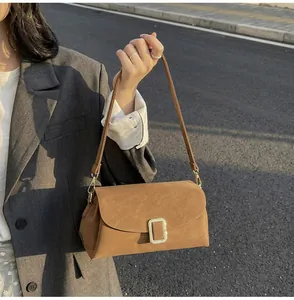 Close-up of a vintage brown suede crossbody bag with elegant gold metal buckle detail