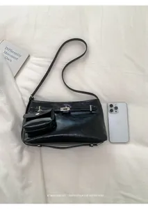 Detailed view of a black glossy shoulder bag with silver buckle and mini pouch accessory