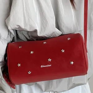 Red cylindrical crossbody bag with silver star rivets and adjustable leather shoulder strap