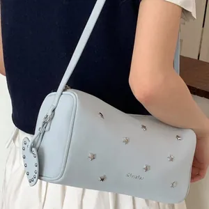 Light blue cylindrical crossbody bag with silver star studs and heart charm accessory