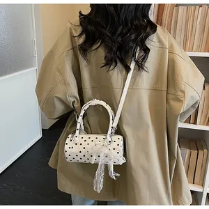 Detailed view of a mini polka dot cylinder bag with lace and pearl pendant decor