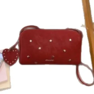 Burgundy faux leather crossbody bag with star metal studs and heart charm accent